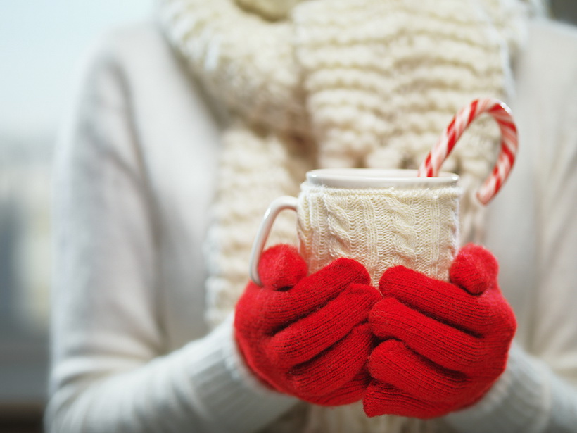 Woman holding winter cup close up on light background. Woman han