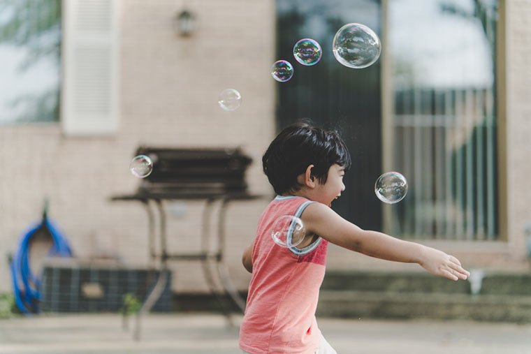 Дитина грає з мильними бульбашками